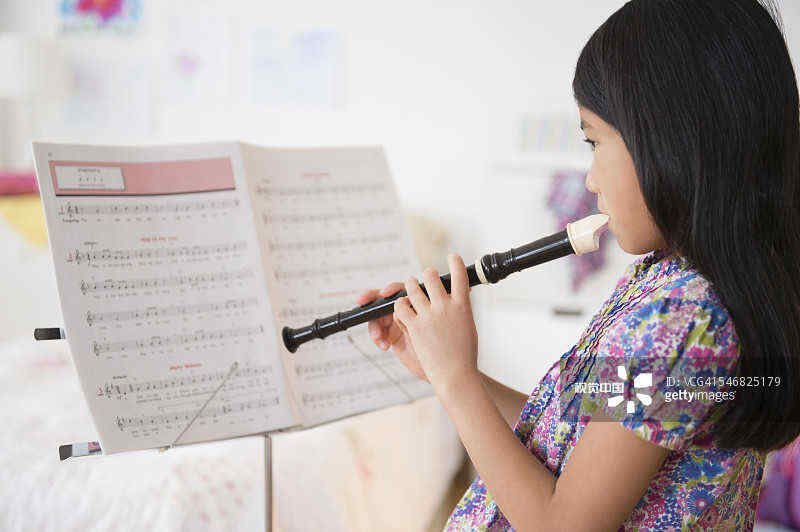 Vietnamese girl playing recorder from sheet music